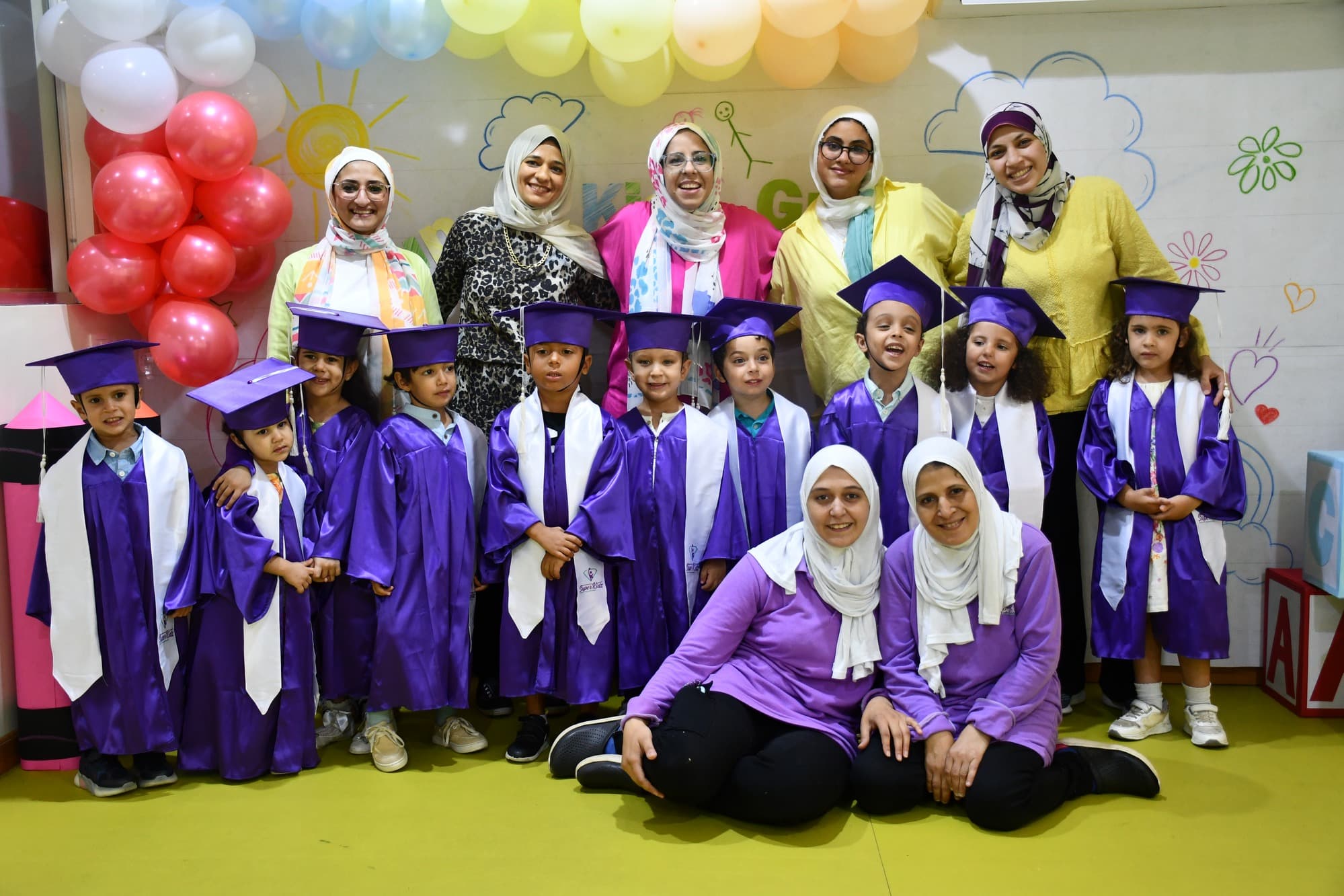 A Super Kidz graduating class posing together in caps and gowns
