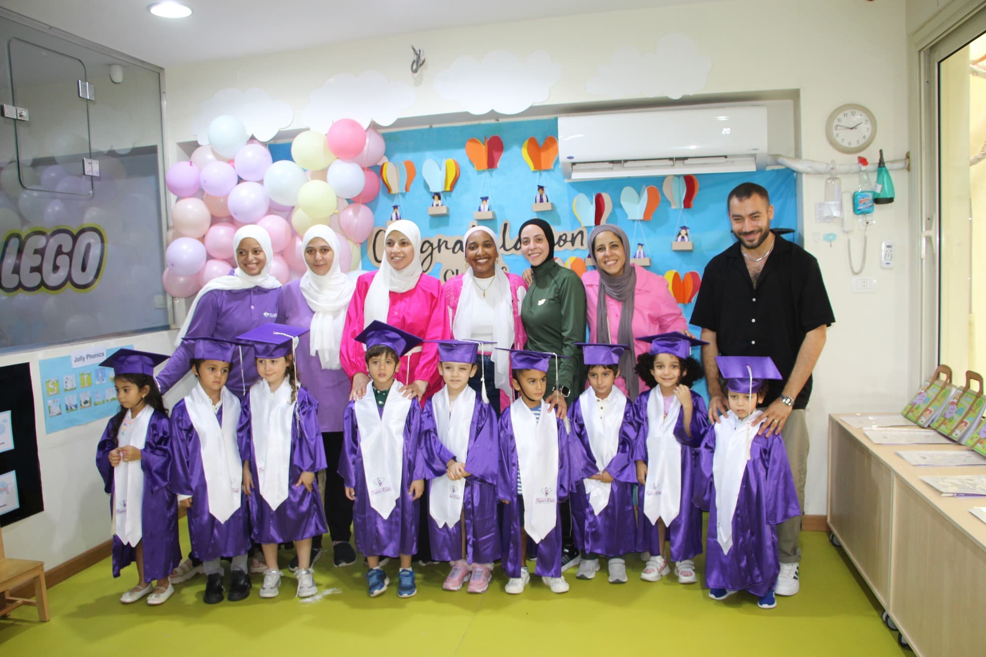 A Super Kidz graduating class posing together in caps and gowns
