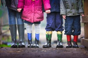 Lower section of four children at SuperKidz nursery standing side by side and facing the camera, showcasing their colorful outfits and shoes, used in a blog post about separation anxiety in kids, offering advice and support for parents.