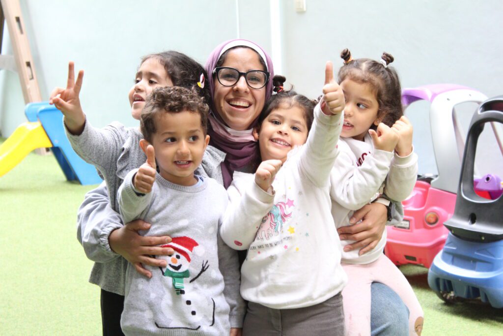 A woman and children smiling together for a photo in the vibrant playroom of Superkidz nursery in Giza, Cairo, Egypt.