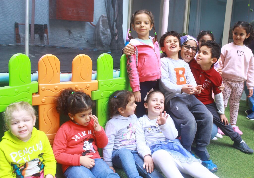 Children gathered on a playground at Superkidz around the nursey founder, engaging in play in Giza, Cairo, Egypt.