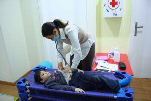 At Superkids Nursery in Cairo, Giza, Egypt, a woman carefully examines a child's chest for health assessment.